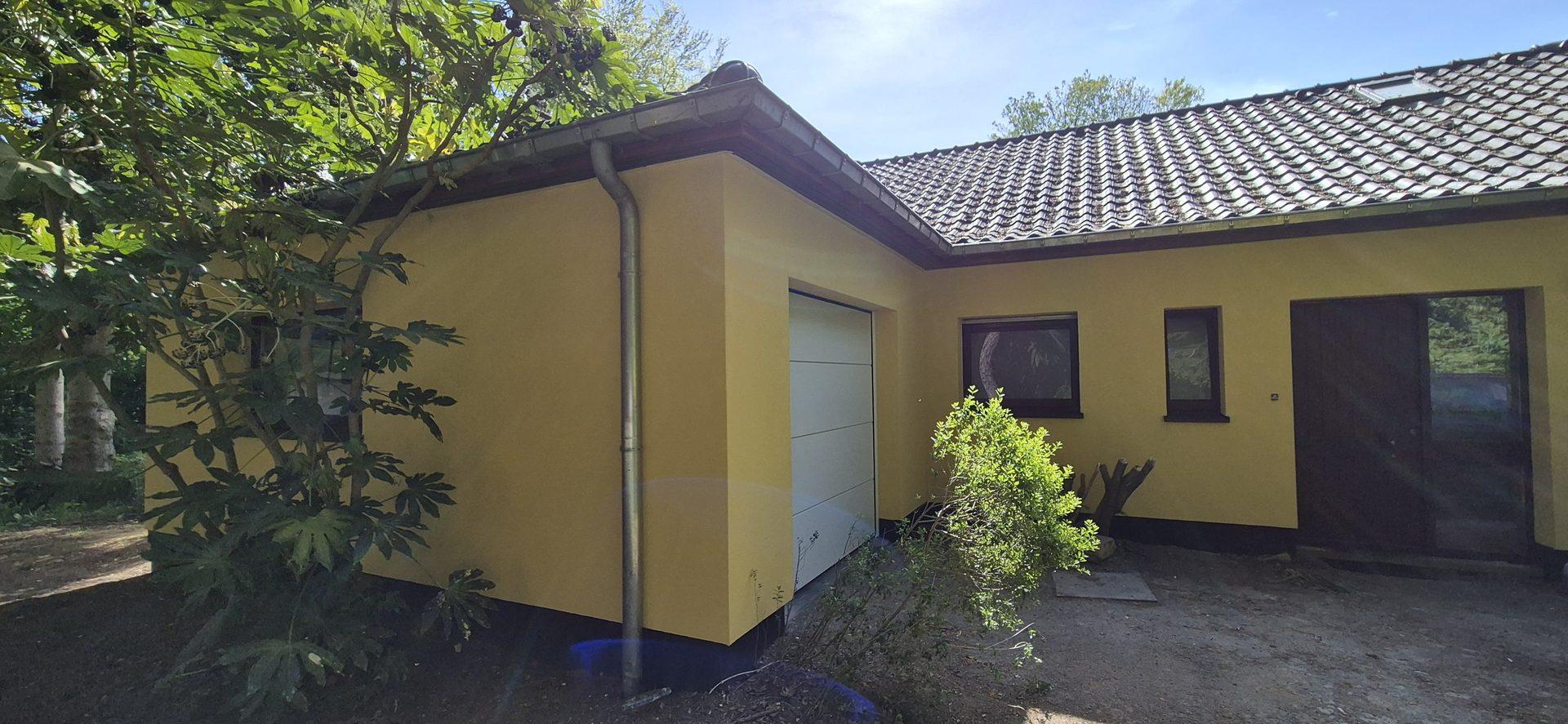Garage en inkom met gele crepi afwerking na gevelwerken in Overijse