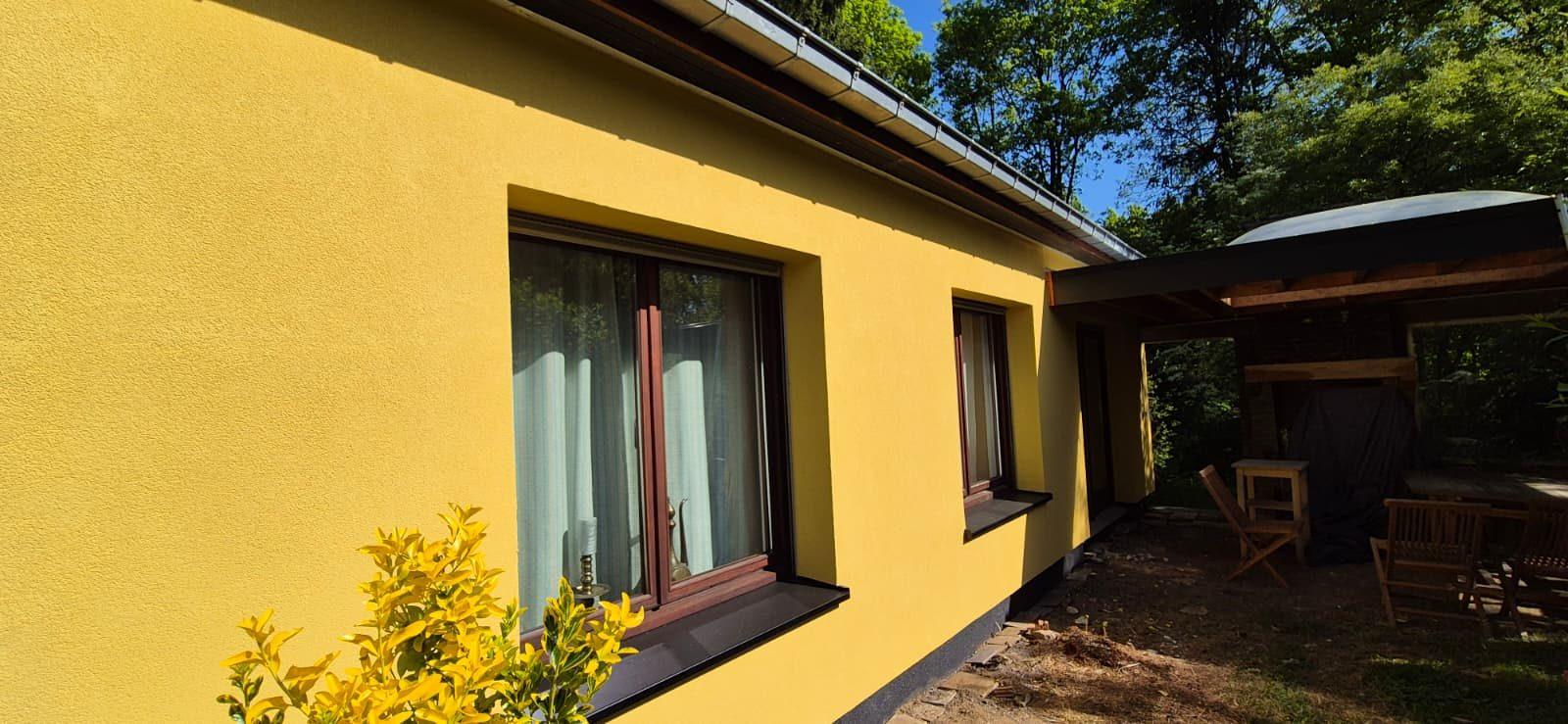 Gele crepi gevel met nieuwe zwarte raamdorpels na buitengevelisolatie in Overijse